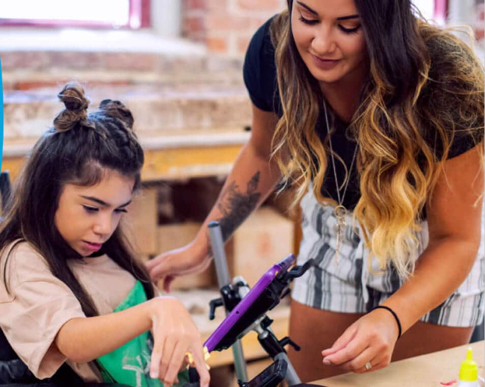 Professional speech pathologist demonstrating for girl how to work with communication device